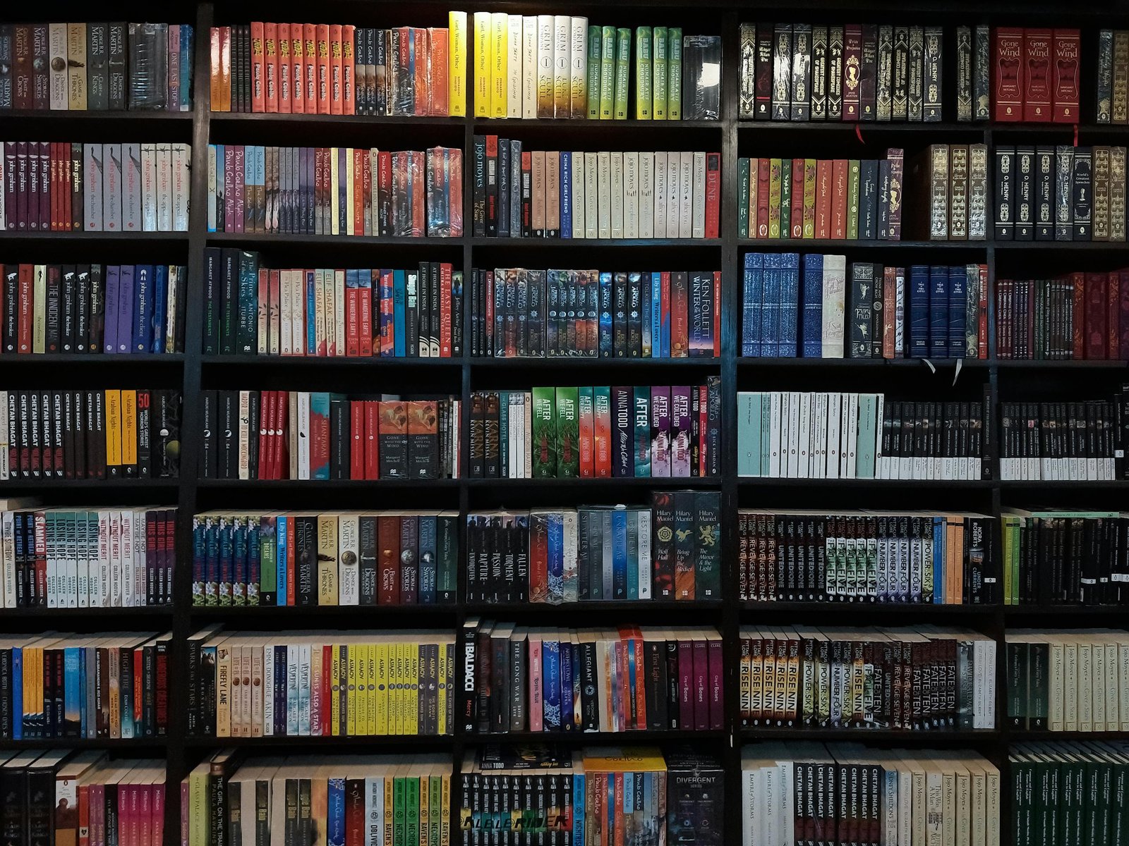 Diverse collection of books on a library shelf in Dhaka, Bangladesh.